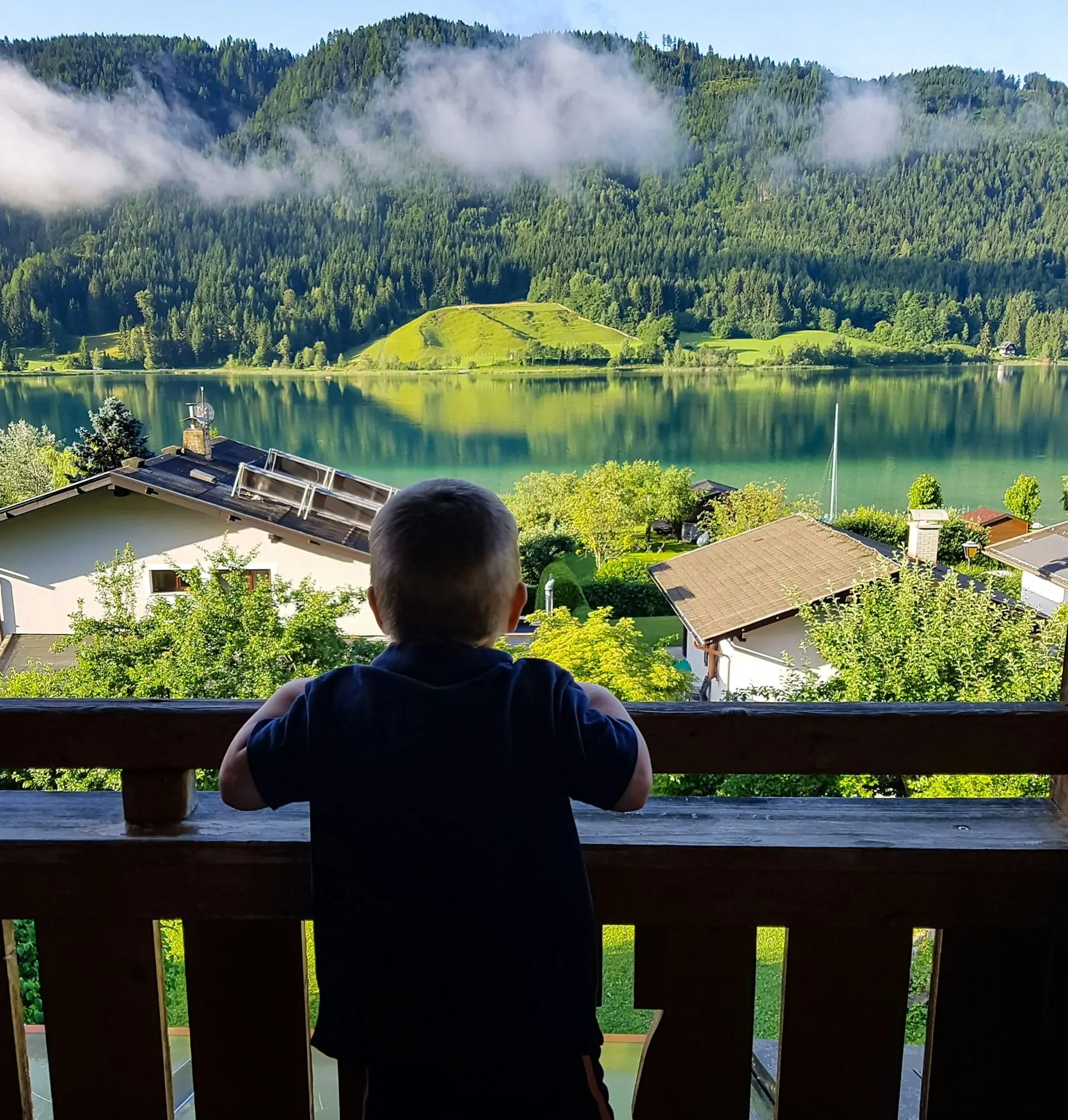 Boy looking at lake and mountains from balcony