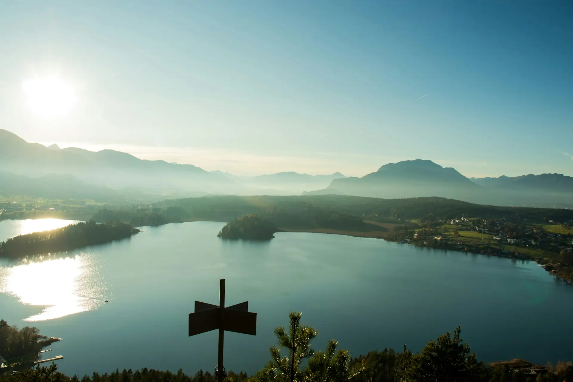 brown cross on top of mountain near body of water during daytime