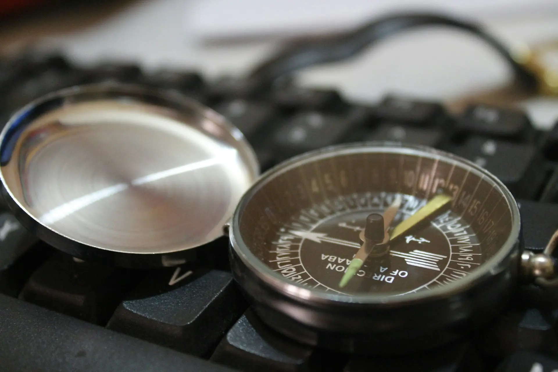 A compass rests on a black keyboard.